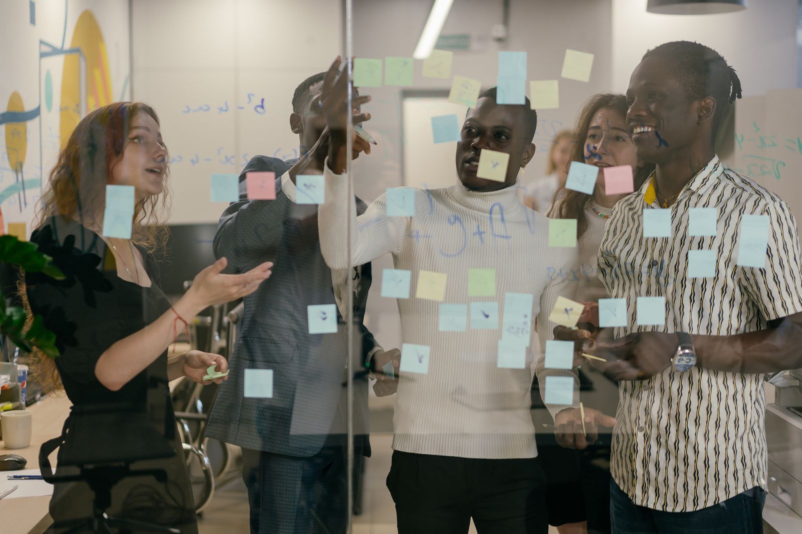 A team mapping a process on a glass wall of notes.