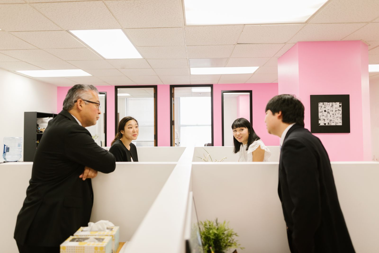 A manager pausing to look across an ordinary, busy workplace.